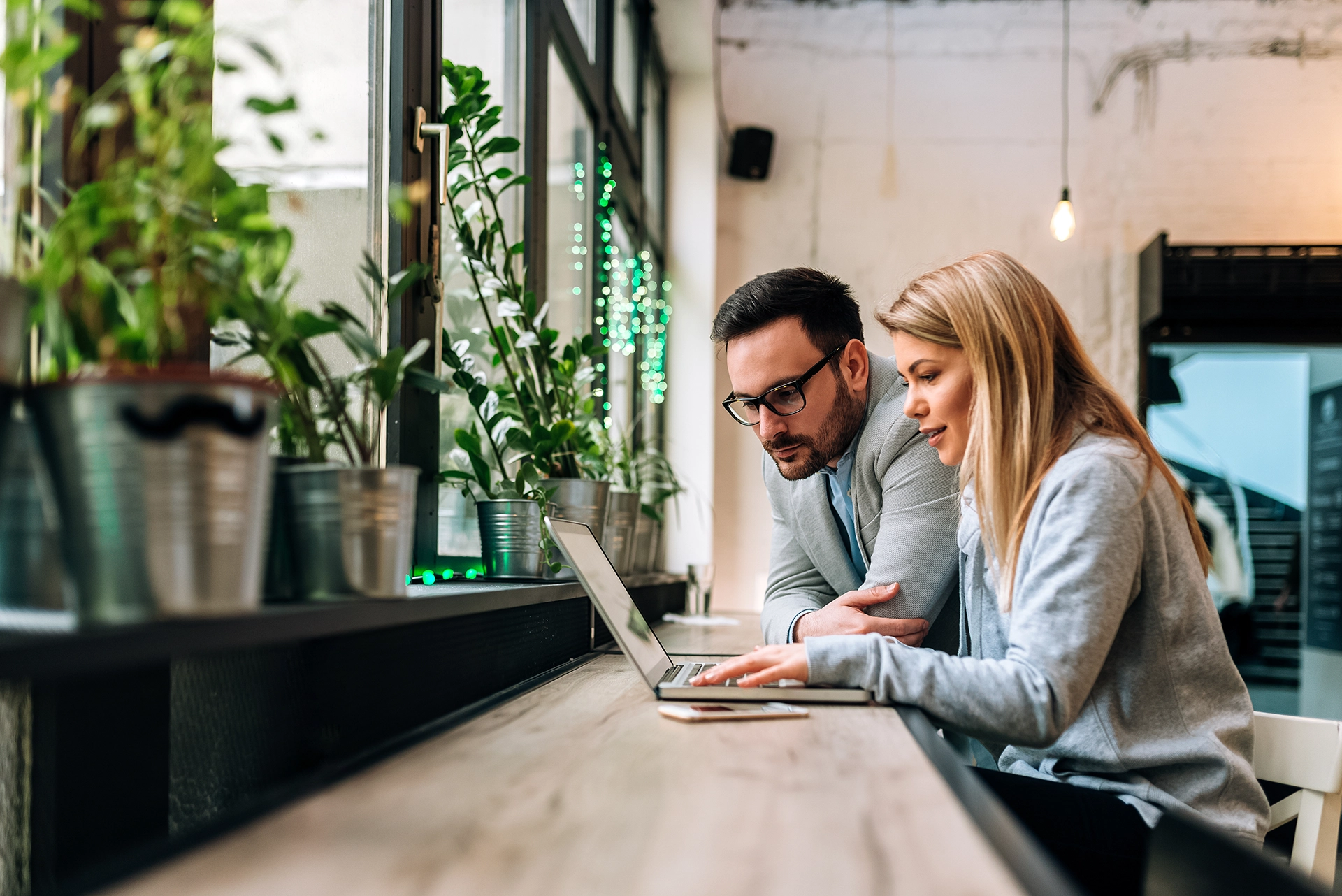 Couple sitting together in a modern café looking at a laptop, researching how to finalize an uncontested divorce peacefully and efficiently.